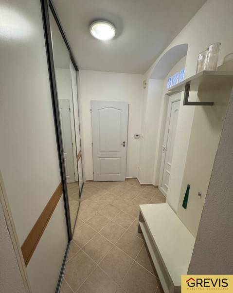 Heller Flur mit Fliesen, Einbauschrank und Bank in einer 2-Zimmer-Wohnung.