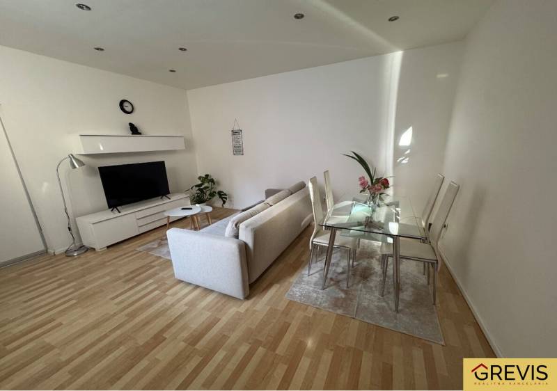 Wohnzimmer in einer Zweizimmerwohnung mit Sofa, Fernseher und Esstisch.