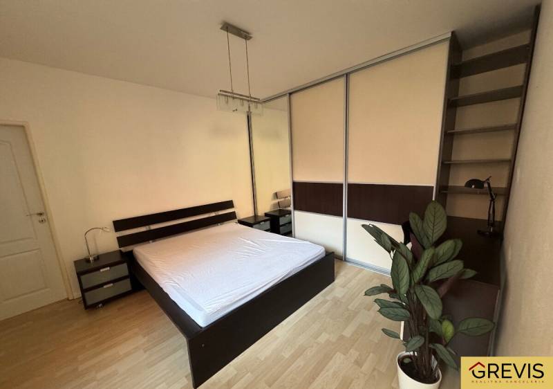 Schlafzimmer mit Einbauschrank, Bett und Nachttischen in einer Zweizimmerwohnung.