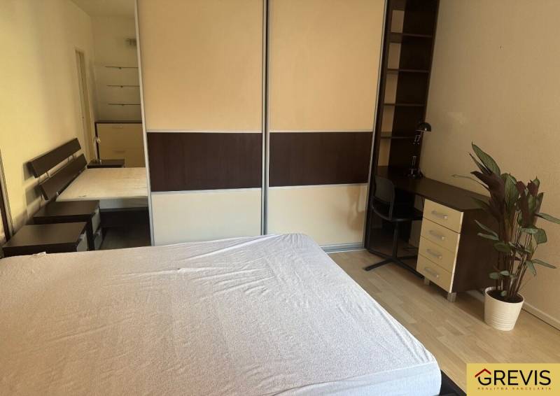 Schlafzimmer in einer 2-Zimmer-Wohnung mit Schrank, Tisch und Pflanze.
