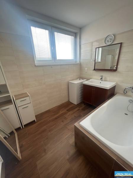 Badezimmer in einer 3-Zimmer-Wohnung mit Badewanne, Spiegel und Holzboden.
