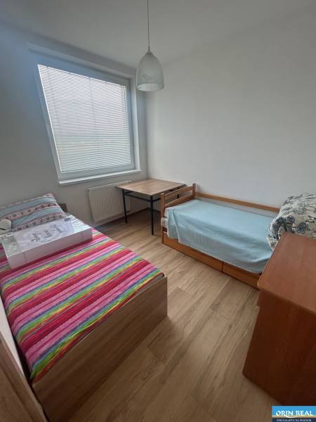 Ein Zimmer in einer 3-Zimmer-Wohnung mit zwei Betten, einem Tisch und Holzboden.