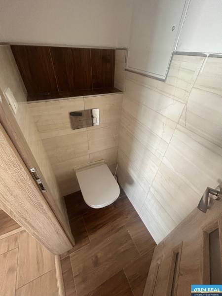 Toilette mit hellen Fliesen und Holzelementen in einer 3-Zimmer-Wohnung.