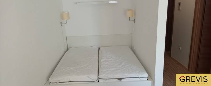 Ehebett mit Lampen an der Wand in einer 2-Zimmer-Wohnung.