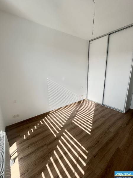Ein leeres Zimmer in einer 3-Zimmer-Wohnung mit Holzboden und Einbauschrank.