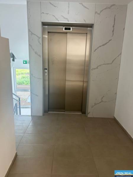 Ein Aufzug im Flur einer 3-Zimmer-Wohnung mit Fliesen und einem Fenster.