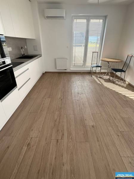 Küche in einer 3-Zimmer-Wohnung mit Holzboden, Esstisch und französischen Fenstern.