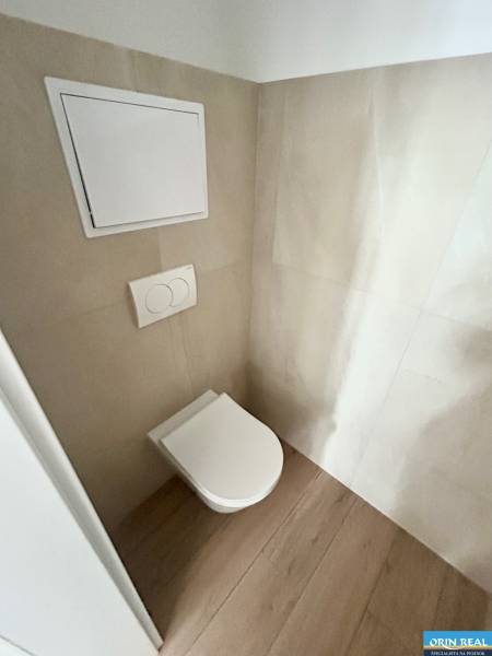 WC mit verstecktem Spülkasten in einer 3-Zimmer-Wohnung, umgeben von hellen Fliesen und Holzboden.