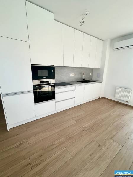 Küche in einer 3-Zimmer-Wohnung mit weißen Schränken, Geräten und Holzboden.