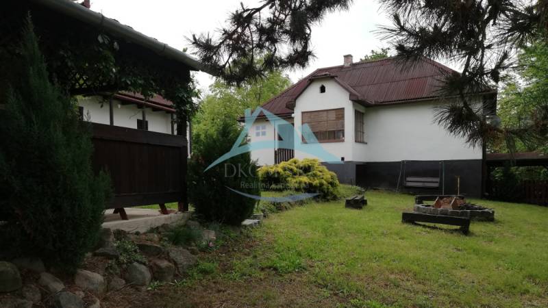 Ein Einfamilienhaus, umgeben von einem Garten, einer Terrasse und einer Feuerstelle, schafft eine angenehme Wohnumgebung.