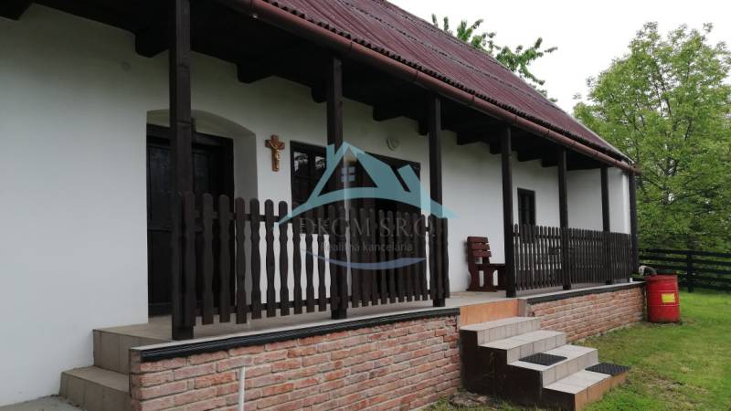Ein Einfamilienhaus mit Terrasse, Holzzaun und Ziegelgrundlage in einer natürlichen Umgebung.