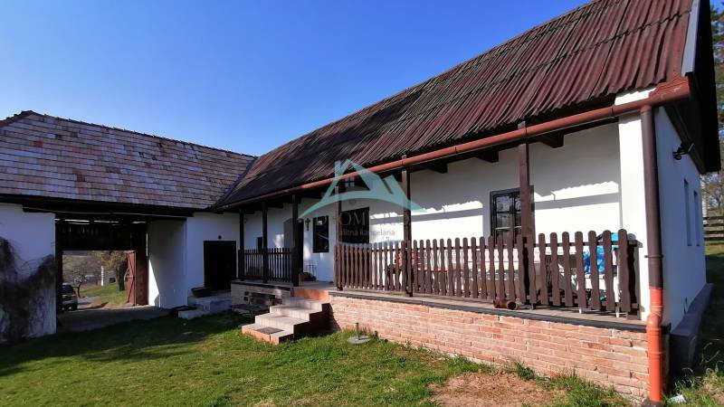 Ein Einfamilienhaus mit Veranda, Holzbalken, Ziegelgrundlage und einem großen Rasen im Garten.