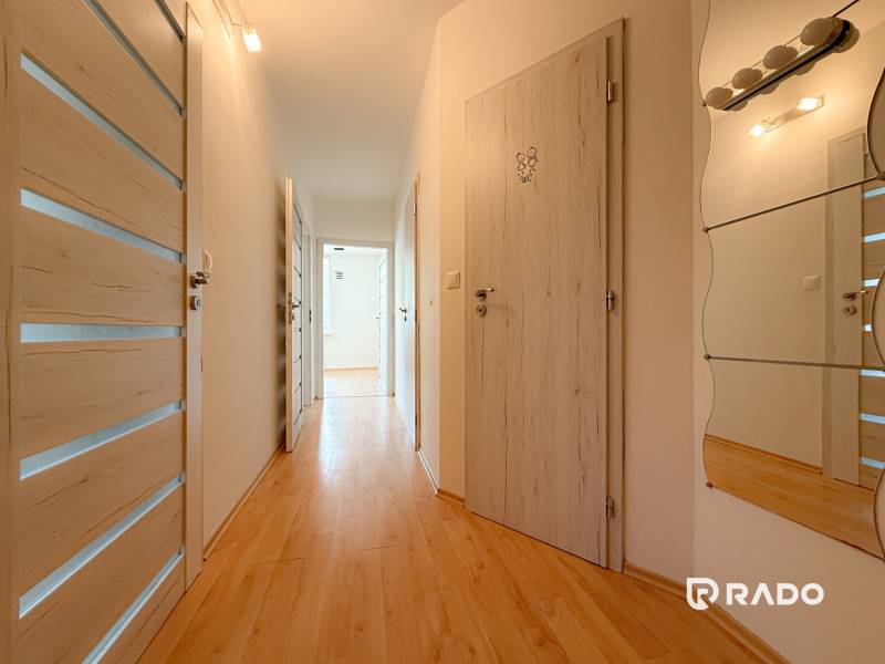Der Flur in einer 3-Zimmer-Wohnung mit Holzboden, weißen Türen und einem Spiegel.