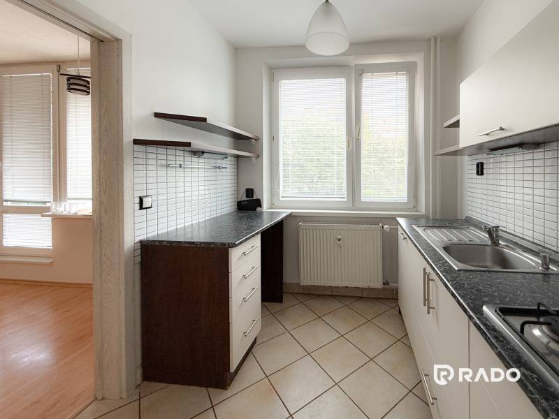 Küche in einer 3-Zimmer-Wohnung mit hellem Fliesenbelag und Möbeln.
