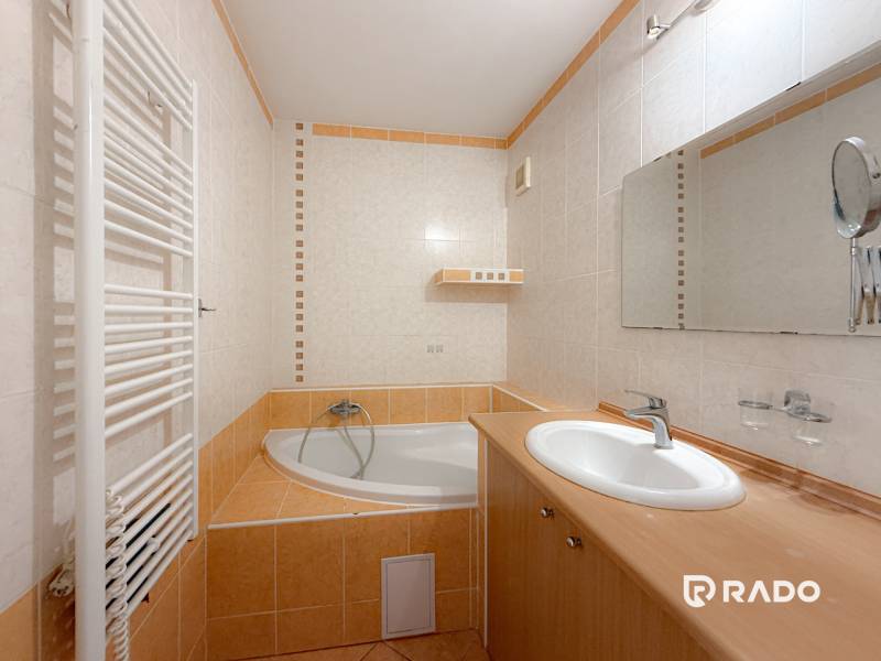 Badezimmer in einer 3-Zimmer-Wohnung mit Eckbadewanne, Waschbecken und Heizkörper.