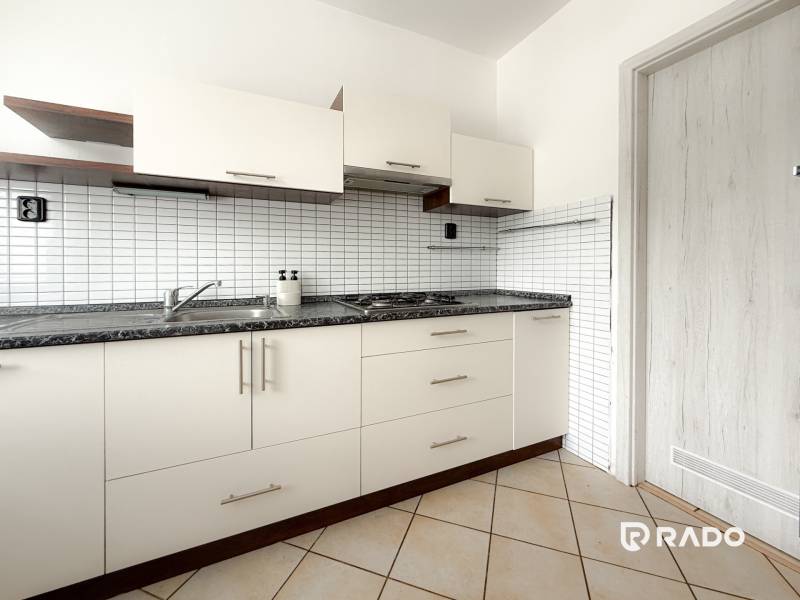 Eine Küchenzeile mit weißen Türen und einer schwarzen Arbeitsplatte in einer 3-Zimmer-Wohnung.