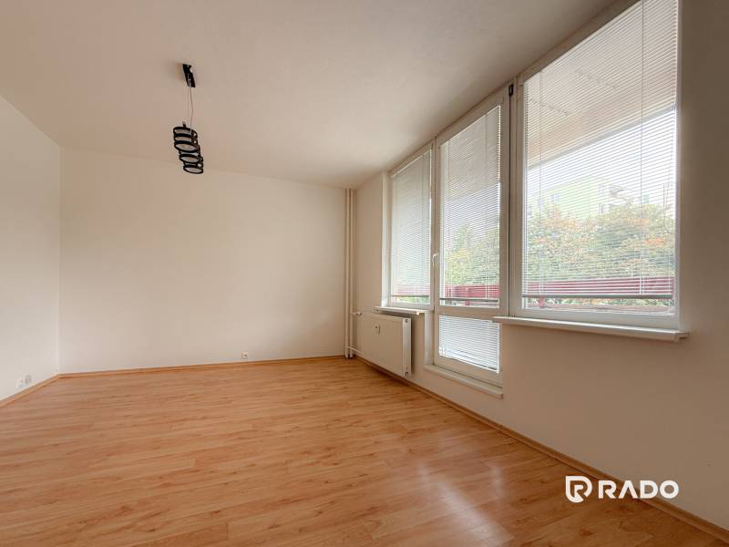 Geräumiges Zimmer mit großen Fenstern und Laminatboden in einer 3-Zimmer-Wohnung.
