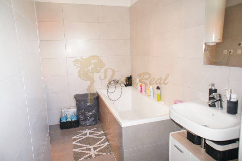 Ein Badezimmer in einem Einfamilienhaus mit einer Badewanne, einem Waschbecken und Aufbewahrungskörben für Wäsche.