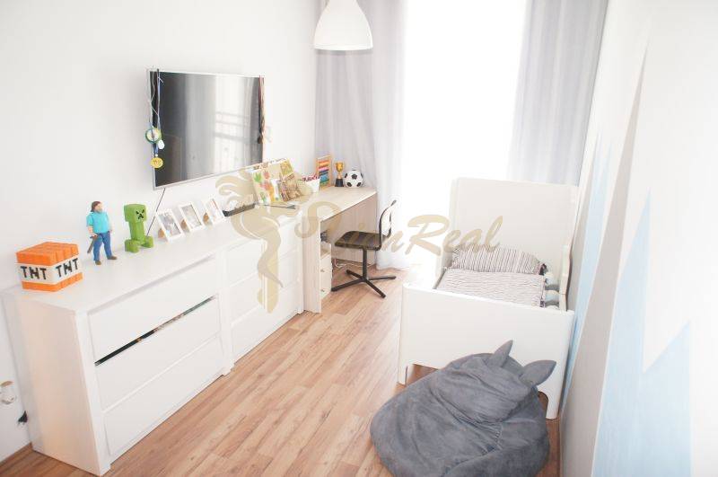 Kinderzimmer in einem Einfamilienhaus mit weißen Möbeln und Holzboden.