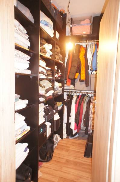 Ein Kleiderschrank mit Regalen und Kleiderbügeln voller Kleidung in einem Einfamilienhaus.