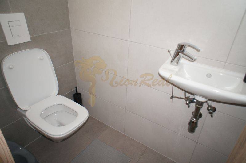 Eine Toilette mit Waschbecken im Einfamilienhaus ist mit Fliesen verkleidet und minimalistisch eingerichtet.