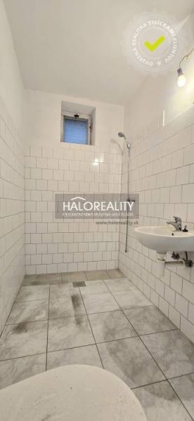 Badezimmer in einem Einfamilienhaus mit weißen Fliesen und Dusche.
