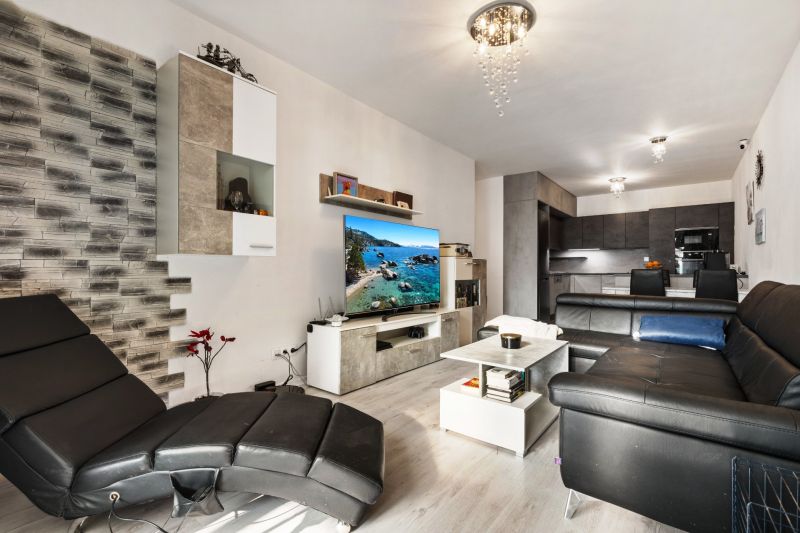 Wohnzimmer einer 3-Zimmer-Wohnung in der Vukovarská-Straße, mit schwarzem Sofa und Fernseher.