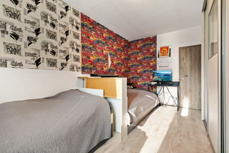Ein Zimmer mit Graffiti-Tapeten, zwei Betten, einem Tisch und einem Fernseher, ideal für Kinder.