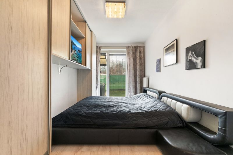 Schlafzimmer mit Bett, Einbauschrank und Blick in den Garten. Geeignet für eine 3-Zimmer-Wohnung in der Vukovarská-Straße.