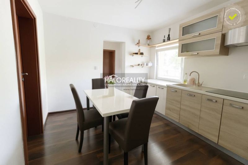 Esszimmer in einem Einfamilienhaus mit weißem Tisch, braunen Stühlen und einem Boden in Holzoptik.