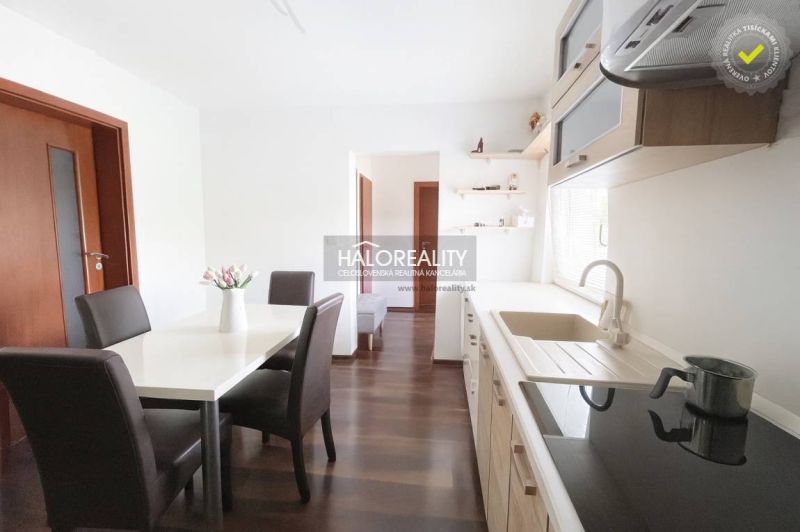 Kücheninterieur eines Einfamilienhauses mit Esstisch und Boden in Holzdekor.
