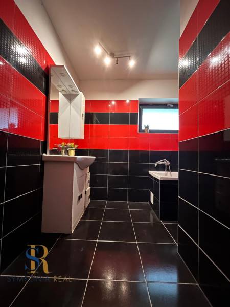 Schwarz-rotes Badezimmer in einem Einfamilienhaus mit Spiegel und Badewanne, auffällige Kombination von Fliesen.