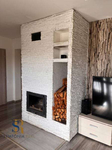 Innenraum eines Einfamilienhauses mit Kamin, Fernseher und Holz, Boden mit Holzdekor.