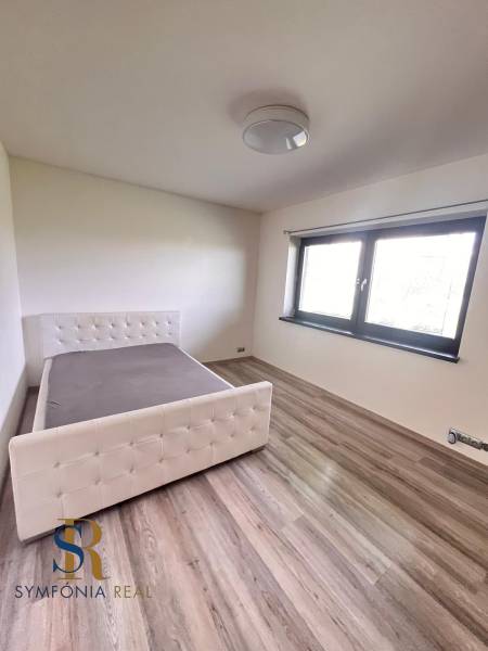 Schlafzimmer im Einfamilienhaus mit Bett und Boden in Holzoptik.