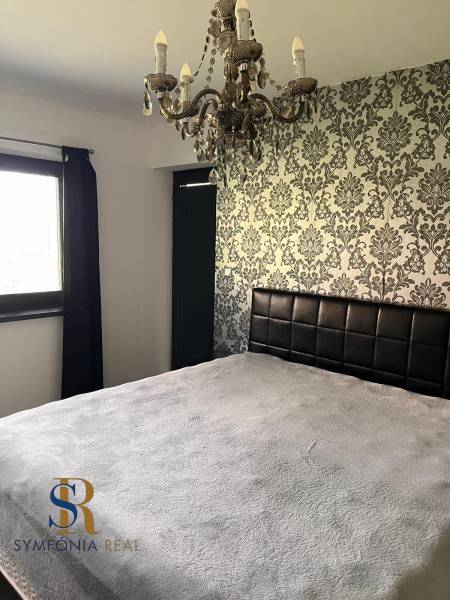 Schlafzimmer im Einfamilienhaus mit dekorativer Tapete und Kronleuchter. Symphonie des Innendesigns.