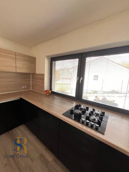 Küche mit Holzdekor und Theke in einem Einfamilienhaus, mit Fenster und Gasherd.