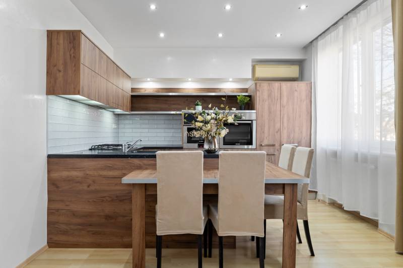 Küche in einer 2-Zimmer-Wohnung mit Holzdekor und hellen Möbeln.