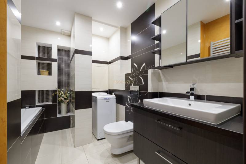 Badezimmer in einer 2-Zimmer-Wohnung mit Dusche, Waschmaschine und Waschbecken.