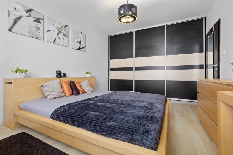 Schlafzimmer in einer 2-Zimmer-Wohnung mit Bett, Schrank und Dekorationen, Boden mit Holzdekor.