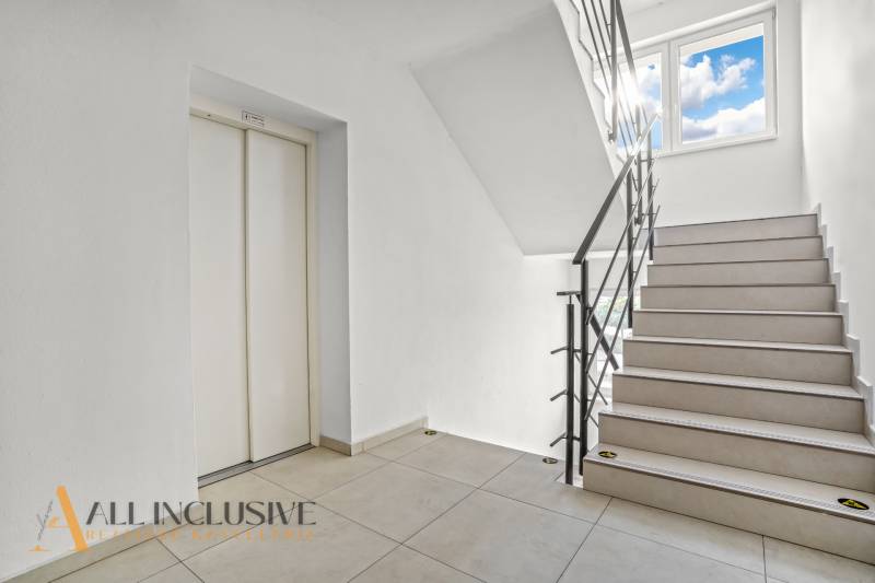 Treppe mit hellem Belag und Aufzug in einer 2-Zimmer-Wohnung.