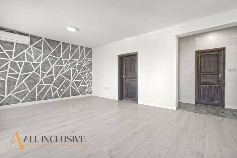 Wohnzimmer mit Holzboden und geometrischer Wand in einer Zweizimmerwohnung.