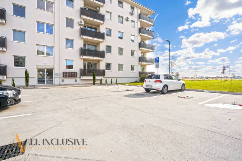 Parkplatz vor dem Wohnhaus in Panónsky háj in Dunajská Streda, mit Autos und einer Rasenfläche.