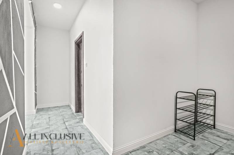 Flur in einer 2-Zimmer-Wohnung mit einem Holzboden und einem Schuhregal.