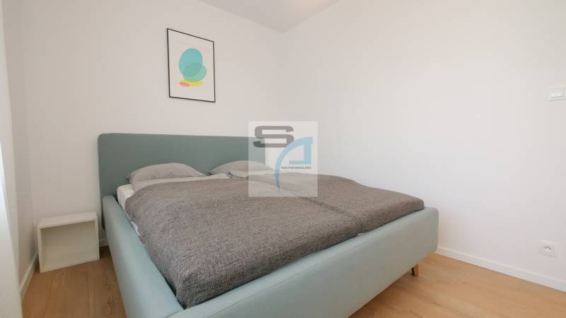 Schlafzimmer mit Bett und minimalistischer Dekoration in einer 2-Zimmer-Wohnung, Boden mit Holzdekor.