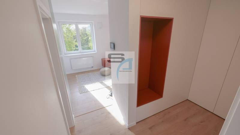 Der Flur in einer 2-Zimmer-Wohnung mit einem Holzboden und Blick in den Raum.