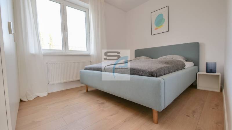 Schlafzimmer in einer 2-Zimmer-Wohnung, helles Bett, Boden mit Holzdekor, einfache Dekoration.