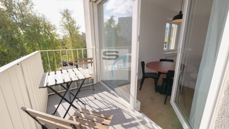 Balkon mit Sitzgelegenheit, Blick ins Grüne und Glastüren in die 2-Zimmer-Wohnung.