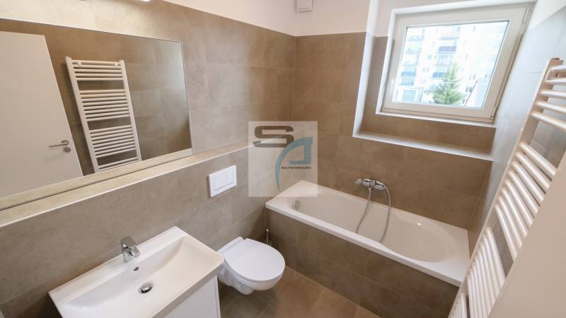 Badezimmer in einer 2-Zimmer-Wohnung mit Badewanne, Waschbecken, Spiegel und Fenster.