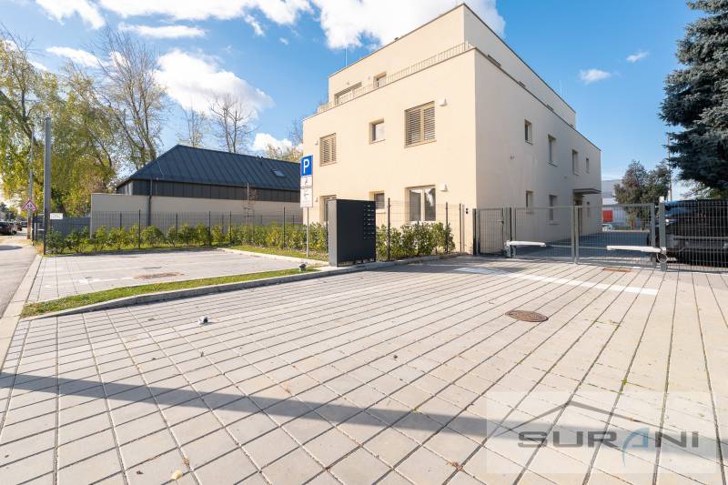 Fassade des Gebäudes in der Železničná-Straße in Bratislava - Vrakuňa, mit Parkplätzen und Grünflächen.