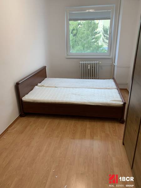 Schlafzimmer in einer 2-Zimmer-Wohnung mit einem Bett und einem Boden in Holzoptik.